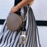 teenyTANKA mit Karabinerhaken an grauer umgehangener Handtasche befestigt