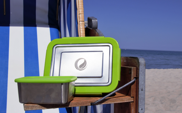 2 Edelstahl Vesperdosen von ECOtanka mit grünem Verschlüssen auf Strandkorbablage und Sandstrand im Hintergrund